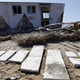 Gravestones are laid out in front of an abandoned structure on the north end of Tangier Island, Virginia. Image via AP Photo/Steve Helber.